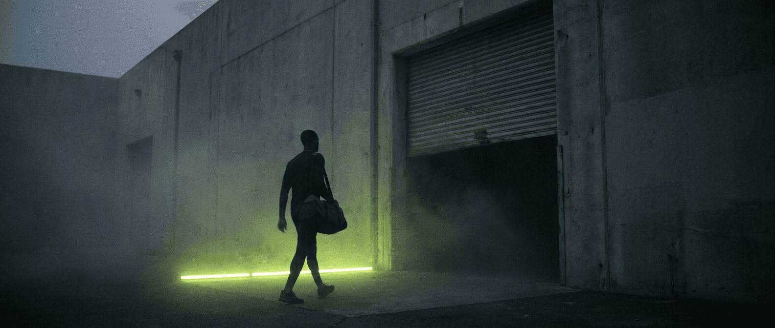 Athlete walking toward a gym entrance lit by a lime light strip